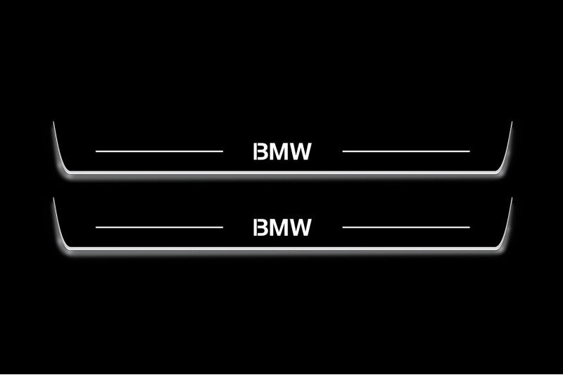 Two long door sill plates with BMW lettering and edges illuminated in white, straight-on view on a dark background.
