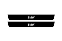 Catalog illustration of two black front door sill plates with BMW lettering.