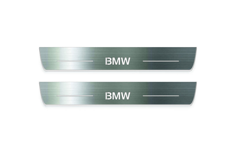 Two long silver-finished door sill plates with BMW lettering on a light background, straight-on view.