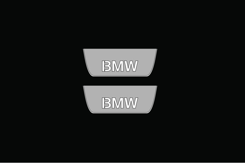 Catalog illustration of two short gray door sill plates with BMW lettering on a black background.
