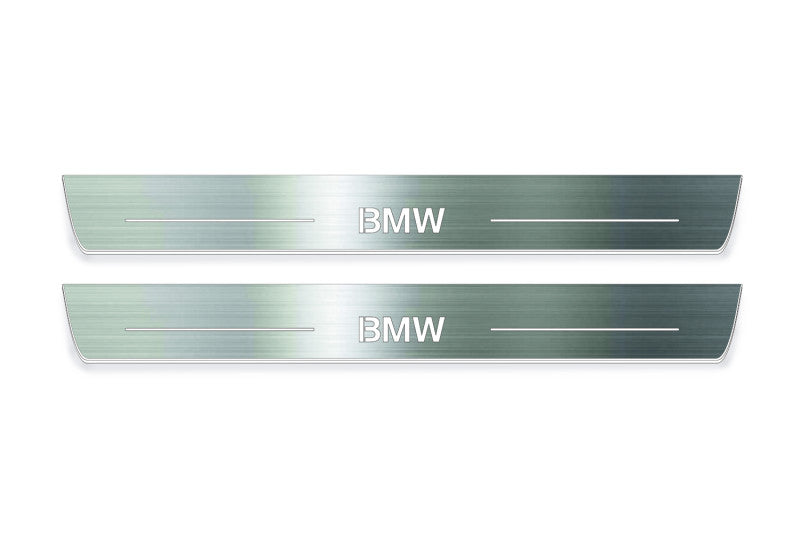 Two long silver-finished door sill plates with BMW lettering on a light background, straight-on view.