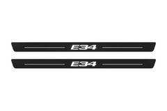 Matte PRO catalogue illustration showing two FRONT plates with illuminated E34 lettering on a white background; BMW 5 Series Sedan E34 dimensions are selected during manufacture; rear plates are not pictured.