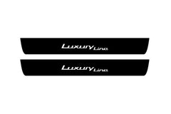 Catalog illustration of two black front door sill plates with Luxury Line lettering.