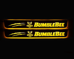 Two door sill plates with yellow Bumblebee lettering, character emblems, two claw marks and illuminated edges.