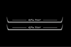 Two long door sill plates with C4 Picasso lettering and edges illuminated in white, straight-on view on a dark background.
