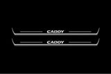 Two long door sill plates with Caddy lettering and edges illuminated in white, straight-on view on a dark background.