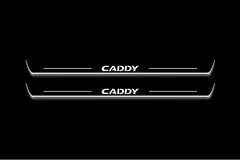 Two long door sill plates with Caddy lettering and edges illuminated in white, straight-on view on a dark background.