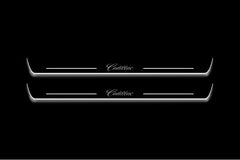 Two long door sill plates with Cadillac lettering and edges illuminated in white, straight-on view on a dark background.