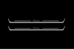 Two long door sill plates with Cadillac in script lettering and edges illuminated in white, straight-on view on a dark background.