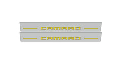Catalog illustration of two gray door sill plates with yellow Camaro lettering and horizontal lines.