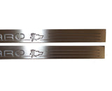 Close-up of Camaro lettering, a character silhouette over a Chevrolet bowtie and horizontal slots on silver-finished door sill plates.