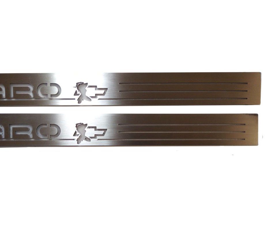 Close-up of Camaro lettering, a character silhouette over a Chevrolet bowtie and horizontal slots on silver-finished door sill plates.