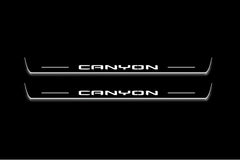 Two long door sill plates with Canyon lettering and edges illuminated in white, straight-on view on a dark background.