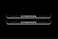 Two long door sill plates with Canyon lettering and edges illuminated in white, straight-on view on a dark background.
