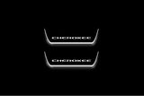 Two short door sill plates with Cherokee lettering and edges illuminated in white, straight-on view on a dark background.