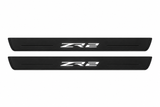 Catalogue illustration of two black Matte PRO front door sill plates with illuminated ZR2 lettering on the upper surface. Decorative lines and edges are unlit; rear plates for FRONT+REAR are not pictured. Dimensions are selected for the Chevrolet Colorado II during manufacture.