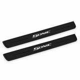 Catalogue illustration of two black Matte PRO front door sill plates with illuminated SONIC lettering on the top surface. The decorative lines and edges are unlit; rear plates for FRONT+REAR are not pictured. Final dimensions are selected for the specific Chevrolet Sonic during manufacture.