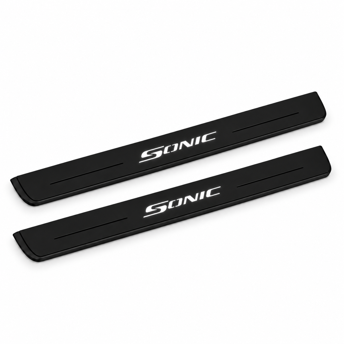 Catalogue illustration of two black Matte PRO front door sill plates with illuminated SONIC lettering on the top surface. The decorative lines and edges are unlit; rear plates for FRONT+REAR are not pictured. Final dimensions are selected for the specific Chevrolet Sonic during manufacture.