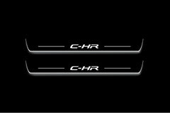 Two long door sill plates with C-HR lettering and edges illuminated in white, straight-on view on a dark background.