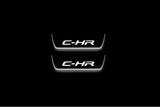 Two short door sill plates with C-HR lettering and edges illuminated in white, straight-on view on a dark background.