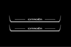 Two long door sill plates with Citroën lettering and edges illuminated in white, straight-on view on a dark background.