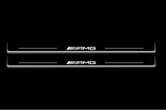 Two long door sill plates with AMG lettering and edges illuminated in white, straight-on view on a dark background.