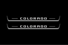 Two long door sill plates with Colorado lettering and edges illuminated in white, straight-on view on a dark background.