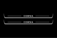 Two long door sill plates with Corsa lettering and edges illuminated in white, straight-on view on a dark background.