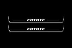 Two long door sill plates with Coyote lettering and edges illuminated in white, straight-on view on a dark background.