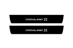 Catalog illustration of two black front door sill plates with Crossland X lettering.