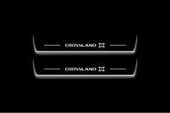 Two long door sill plates with Crossland X lettering and edges illuminated in white, straight-on view on a dark background.