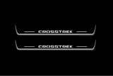Two long door sill plates with Crosstrek lettering and edges illuminated in white, straight-on view on a dark background.