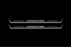 Two long door sill plates with Crosstrek lettering and edges illuminated in white, straight-on view on a dark background.