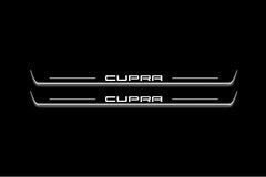 Two long door sill plates with Cupra lettering and edges illuminated in white, straight-on view on a dark background.