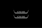 Two short door sill plates with CX-30 lettering and edges illuminated in white, straight-on view on a dark background.