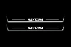 Two long door sill plates with Daytona lettering and edges illuminated in white, straight-on view on a dark background.