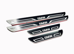 Four reflective door sill plates with BMW lettering and angular border designs on a white background.