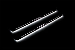Two long door sill plates with Tiggo 8 lettering and edges illuminated in white, angled view on a dark background.