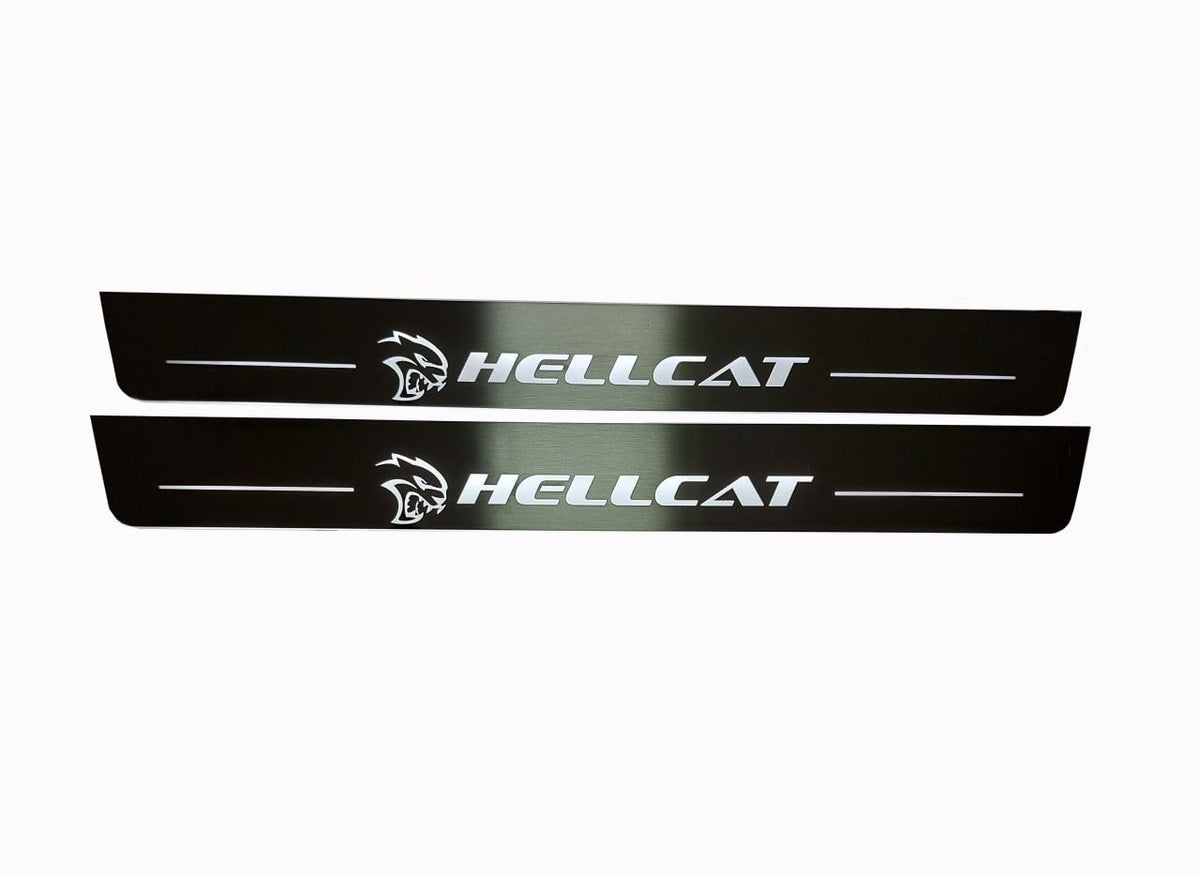 Two long dark reflective door sill plates with white Hellcat lettering and head emblems.
