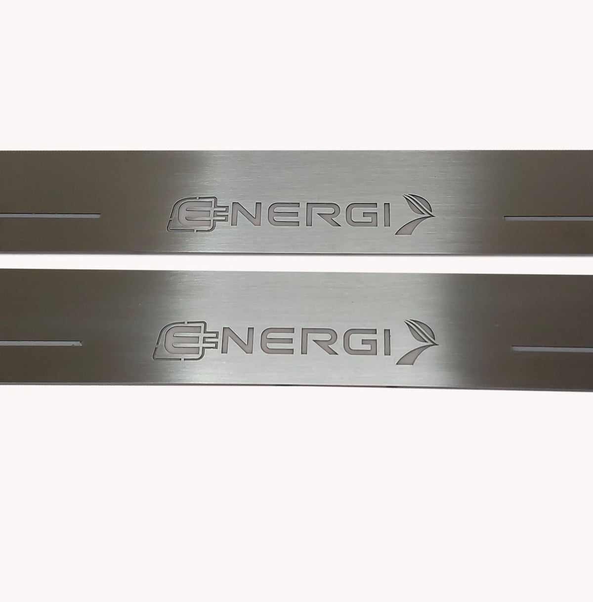 Close-up of unframed Energi lettering with a plug and arrow on two silver-finished door sill plates.