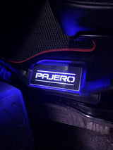 Short rectangular Pajero plate illuminated beside a vehicle floor mat; installation example.