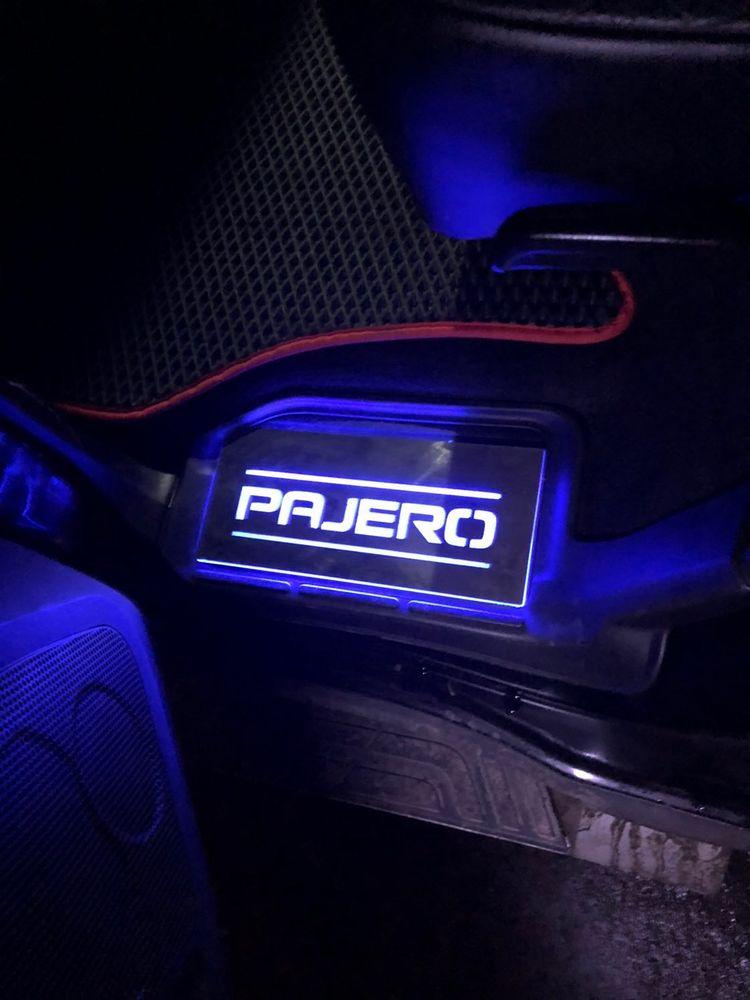 Short rectangular Pajero plate illuminated beside a vehicle floor mat; installation example.
