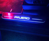 Long Pajero door sill with white illuminated lettering on a vehicle threshold beside a red-trimmed floor mat.
