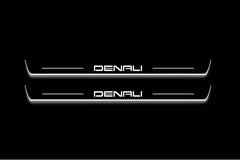 Two long door sill plates with Denali lettering and edges illuminated in white, straight-on view on a dark background.