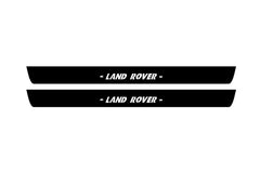 Catalog illustration of two black front door sill plates with Land Rover lettering.