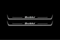 Two long door sill plates with Doblò lettering and edges illuminated in white, straight-on view on a dark background.