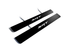 Two black door sill plates with white SRT lettering and visible wiring on a light background.