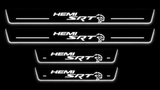 Four Dodge SRT HEMI Hellcat stainless steel door sills with white illuminated lettering, light bars and edges against a black background.