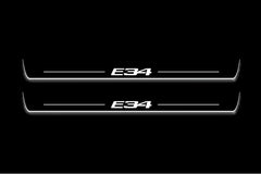 Two long door sill plates with E34 lettering and edges illuminated in white, straight-on view on a dark background.