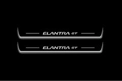 Two long door sill plates with Elantra GT lettering and edges illuminated in white, straight-on view on a dark background.